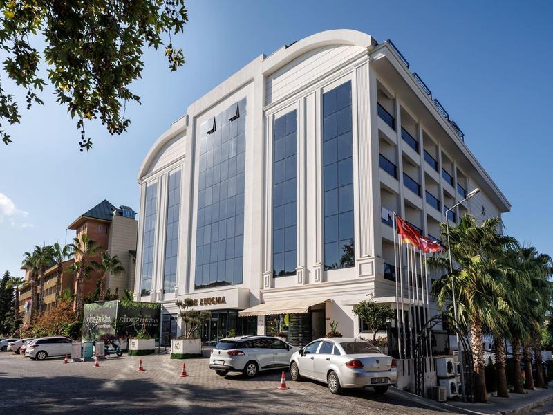 Modern hotel building with large glass facade and flags at the entrance.