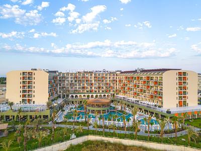 Groot resort met zwembad en palmbomen onder blauwe lucht.