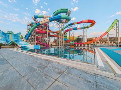 Kleurrijk waterglijbaan- en zwembadcomplex onder een heldere hemel bij een vakantiepark.