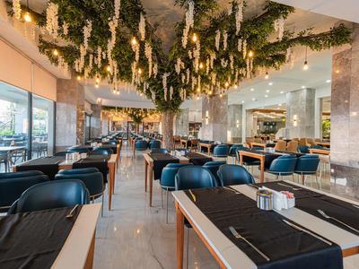 Modern restaurant met hangende boomdecoratie en zwarte tafelkleden