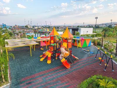 Kleurrijke kinderspeelplaats met glijbanen, klimrekken en schommels in de buitenlucht onder een heldere hemel.