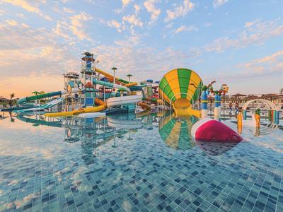 Waterpark met grote glijbanen en helder zwembad bij zonsondergang.