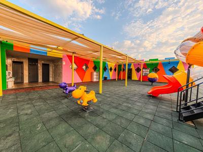 Kleurrijke speeltuin met glijbaan en wip op dakterras onder blauwe lucht.