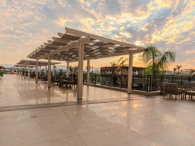 Groot terras met pergola's en zitgedeeltes bij zonsondergang in een hotel.