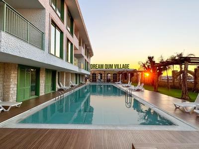 Modern buitenzwembad met ligstoelen naast een hotelgebouw bij zonsondergang.