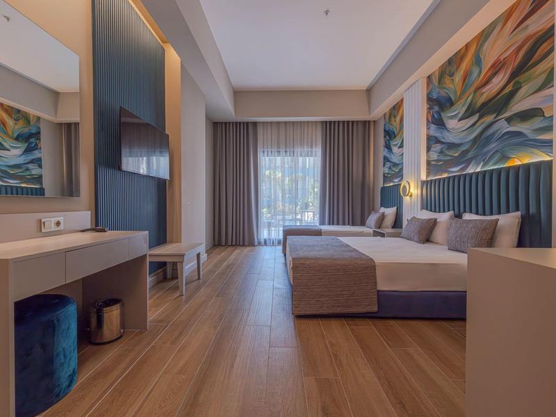 Moderne hotelkamer met tweepersoonsbed, houten vloer en groot raam met uitzicht op groen.