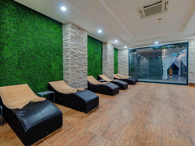 Moderne ontspanningsruimte met ligstoelen en groene muur in een hotel.