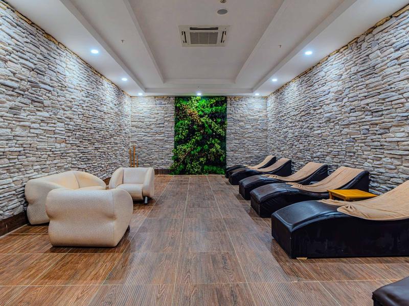 Moderne wellnessruimte met comfortabele ligstoelen en witte fauteuils naast stenen muren.