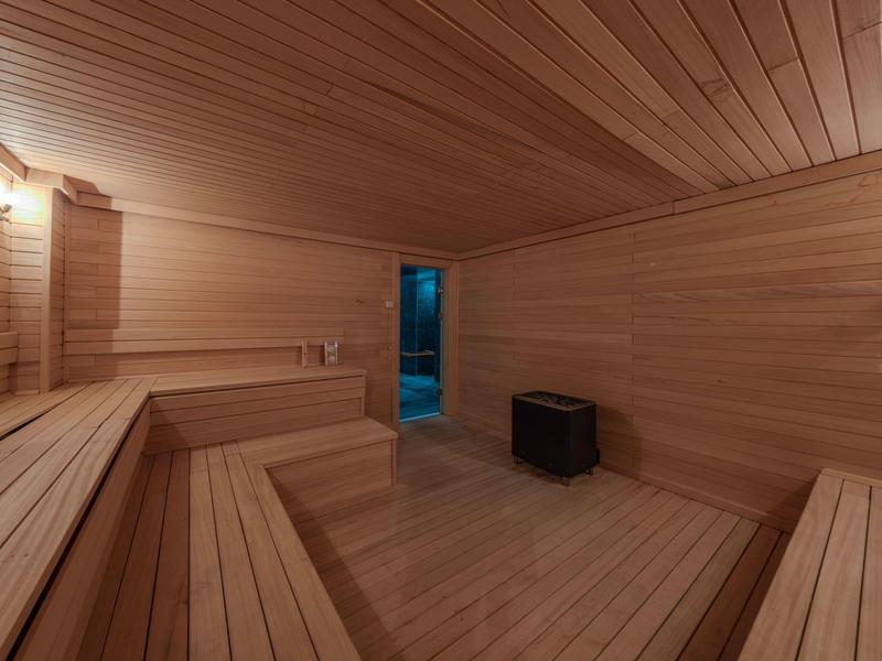 Interieur van een houten sauna met lange bankrijen en een kachel onder het plafond.