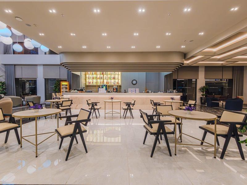 Helder verlichte moderne hotelbar met tafels en stoelen op glanzende vloer.