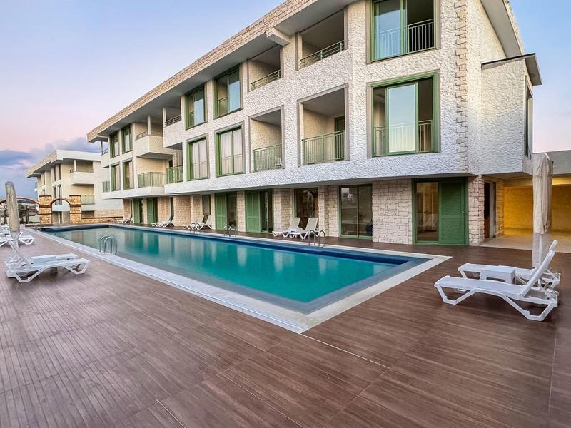 Modern hotelzwembad met ligstoelen en groot terras bij zonsondergang.