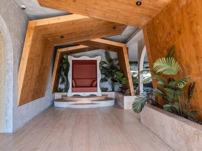 Moderner Eingangsbereich mit geometrischem Holzdesign und Pflanzen in einem Hotel.