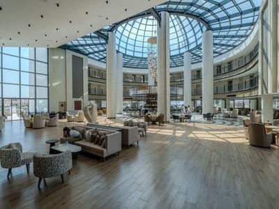 Großer Hotel-Loungebereich mit bodentiefen Fenstern und viel Tageslicht.