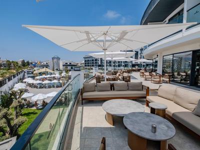 Elegante Hotelterrasse mit bequemen Sitzgelegenheiten und Schirmen, Blick auf den Garten und Pool.