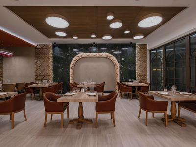 Elegantes Restaurant mit moderner Beleuchtung, Holzmöbeln und stilvoller Wanddekoration.