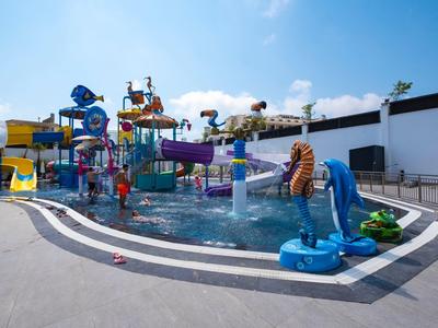Wasserpark mit bunten Rutschen und Wasserspielgeräten unter blauem Himmel.