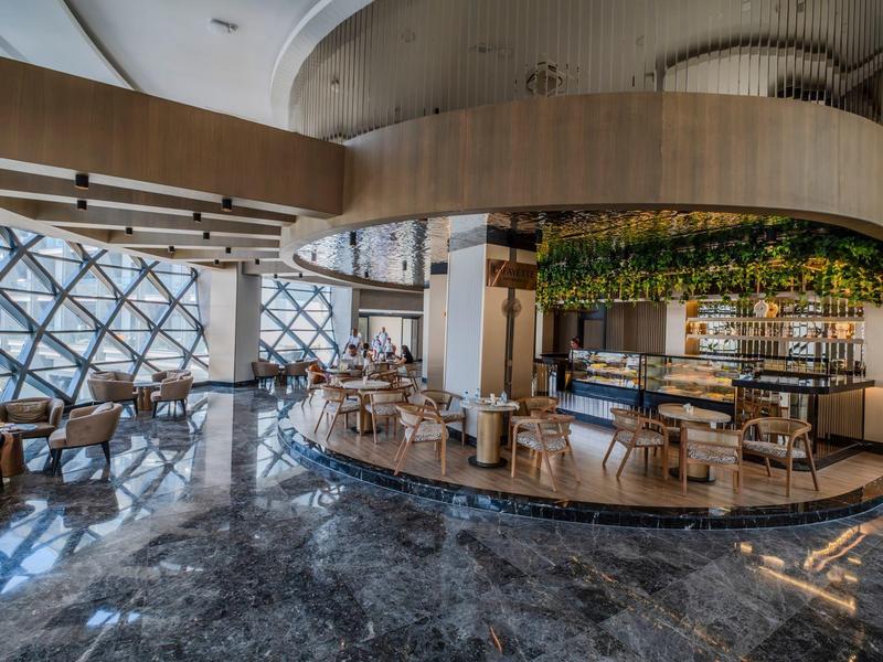 Modernes Hotel-Lounge mit Glasfassade, stilvollen Sitzecken und Marmorboden.