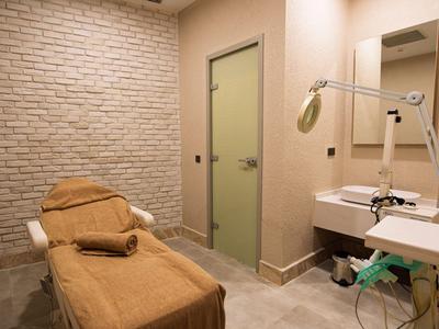 Ošetřovací místnost s lehátkem, ručníky a umyvadlem, jemné osvětlení.