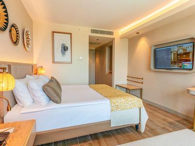 Moderní hotelový pokoj s manželskou postelí, dřevěnou podlahou a stylovou dekorací stěn.