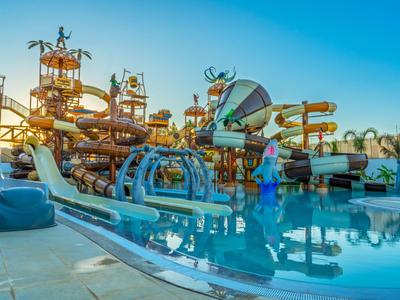 Barevný vodní park se skluzavkami a vodními atrakcemi osvětlený při západu slunce.