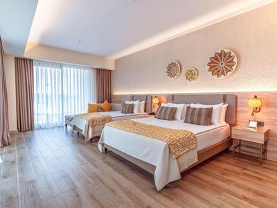 Moderní hotelový pokoj se dvěma postelemi, dřevěnou podlahou a velkým oknem s závěsy.