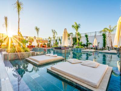 Luxusní lehátka s polštáři na hladině vody při západu slunce v hotelu