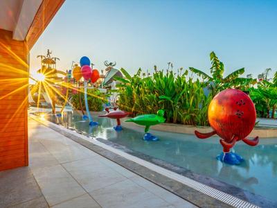 Západ slunce nad bazénem s vodními hřišti a skluzavkou v tropické zahradě