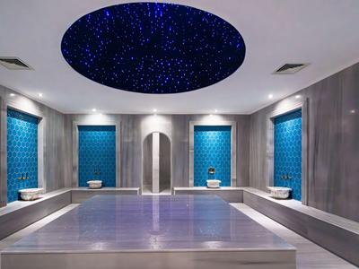 Luxusní hammam s modře osvětleným hvězdným stropem a šedými stěnami.