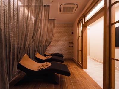 Relaxacní místnost s lehátky a průsvitnými záclonami v teplém osvětlení.