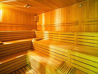 Interiér dřevěné sauny s lavicemi a teplým osvětlením.