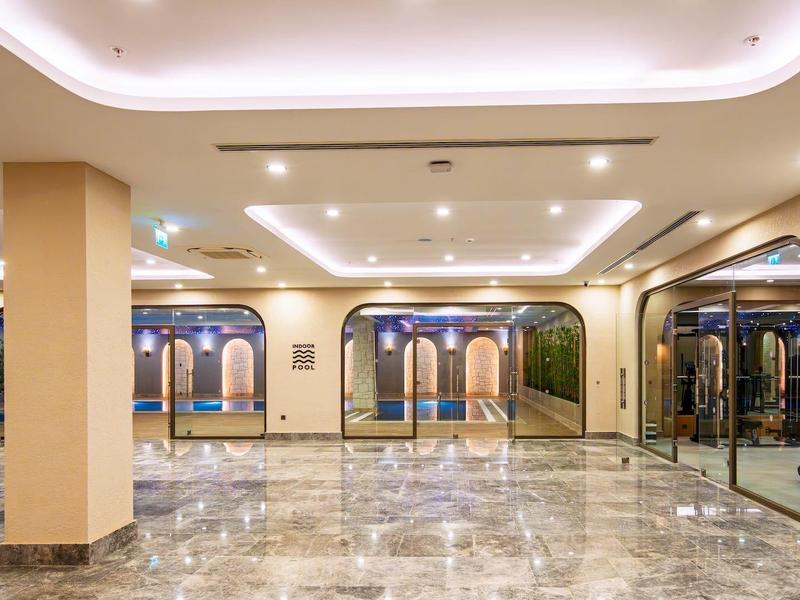 Großer, heller Saal mit glänzendem Marmorfußboden, Säulen und Spiegeln an den Wänden.