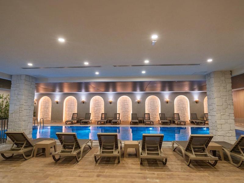 Moderner Indoor-Pool mit blauen Wasser, Liegestühlen in Reihe und runden Wandnischen mit Beleuchtung.