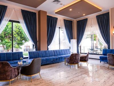 Hall d'hôtel lumineux avec grandes fenêtres, rideaux bleu foncé et mobilier moderne.