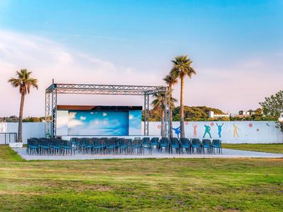 Scène en plein air avec rangées de sièges et palmiers au coucher du soleil