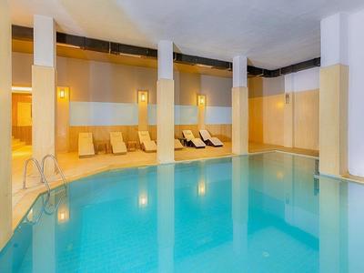 Piscine intérieure lumineuse et moderne avec chaises longues et colonnes de soutien dans un espace bien-être tranquille.