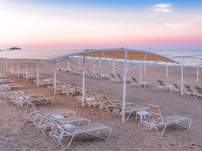 Plage de sable vide avec chaises longues et parasols au coucher du soleil au bord de la mer