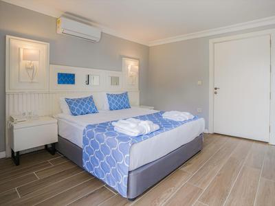 Chambre d'hôtel lumineuse avec lit double, coussins bleus et sol en bois.