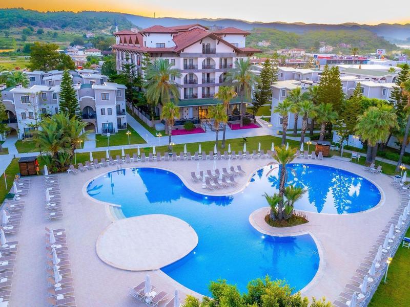 Grande piscine extérieure en forme courbée, entourée de transats dans un complexe hôtelier.