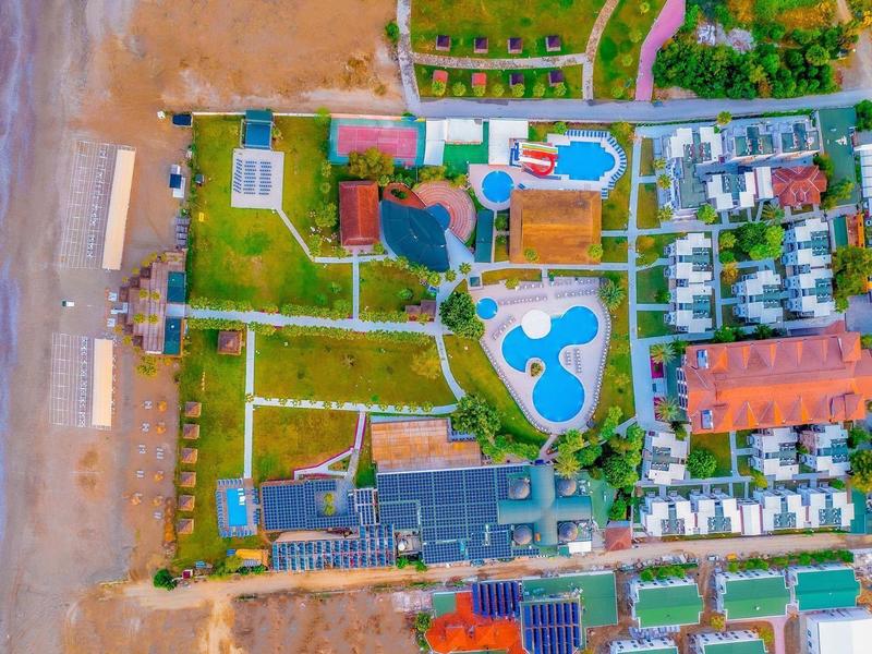 Vue aérienne d'un complexe en bord de mer avec piscine, divers bâtiments et accès direct à la mer.
