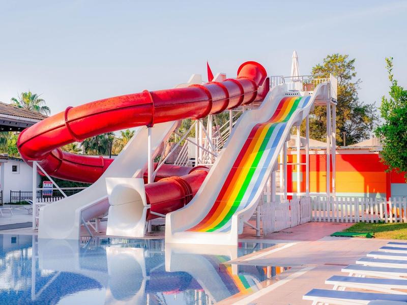 Toboggans rouges et colorés dans une piscine extérieure en plein soleil.