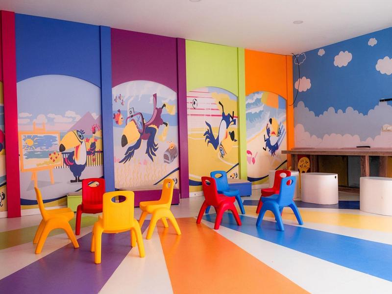 Salle de jeux colorée pour enfants avec petites chaises et fresques murales animées.
