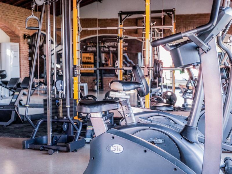 Salle de sport moderne avec diverses machines d'entraînement et miroirs.