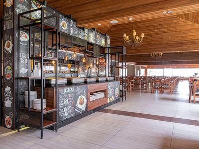 Nowoczesna restauracja hotelowa z barem, drewnianym sufitem i dużą ilością naturalnego światła.