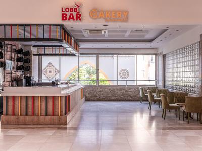 Espace bar moderne dans le hall d'hôtel avec des couleurs vives et des sièges près de grandes fenêtres.