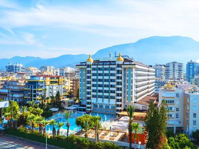 Paysage urbain avec hôtels, piscine et montagnes en arrière-plan sous un ciel bleu.