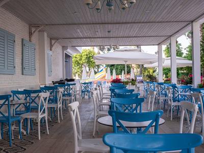 Espace café extérieur couvert avec des chaises et tables bleues et blanches