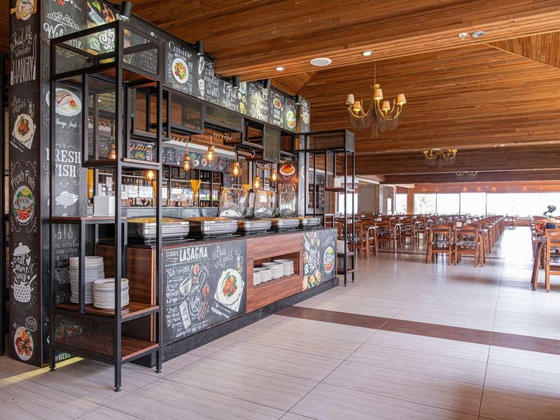 Bar moderne avec plafond en poutres en bois et nombreuses tables dans un restaurant spacieux.