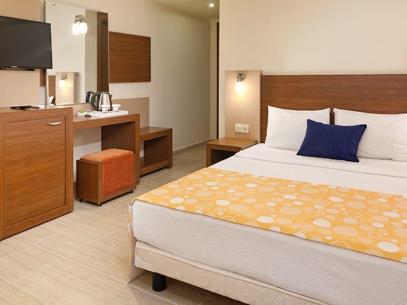 Chambre d'hôtel moderne avec lit double, meubles en bois et télévision murale.