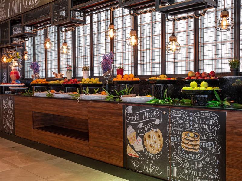 Un buffet moderne avec des fruits frais, des légumes et des panneaux décoratifs dans un restaurant.