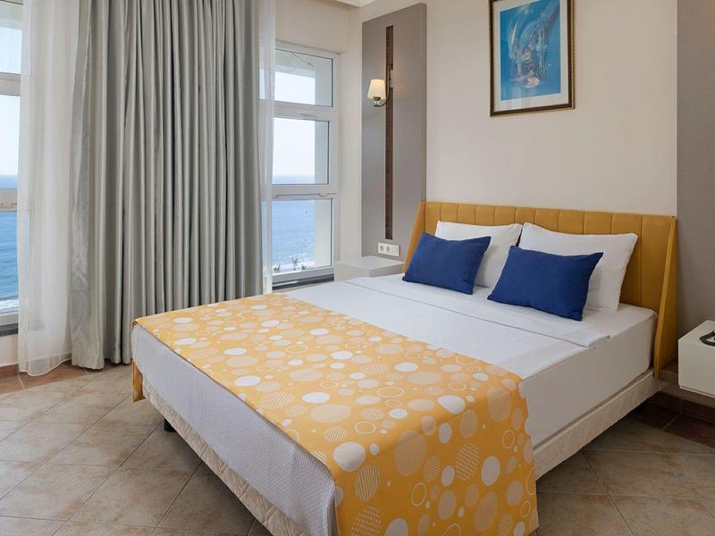 Chambre d'hôtel moderne avec grand lit, vue sur la mer et décor minimaliste.